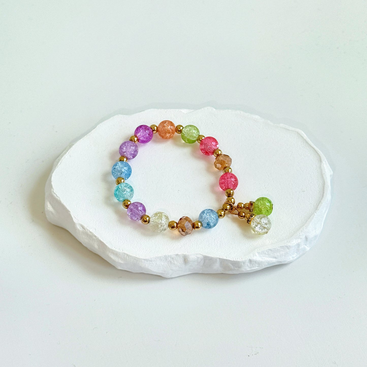 A simple, cute bracelet with 13 light colored glass beads in the colors of a flower garden, clasped with a dangling last pair of glass beads.