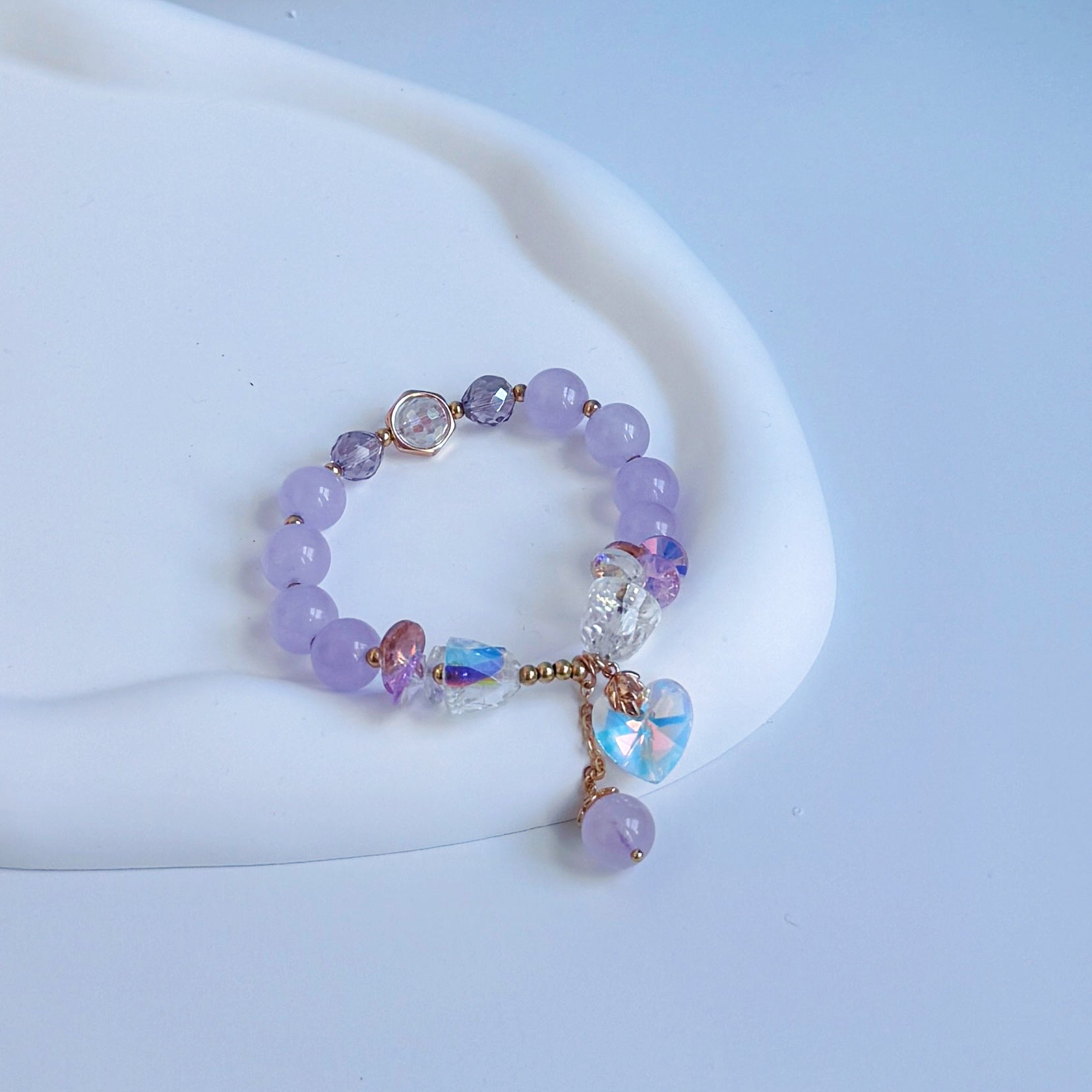 Pink jade beaded bracelet with crystal charms, including one in the shape of a heart.