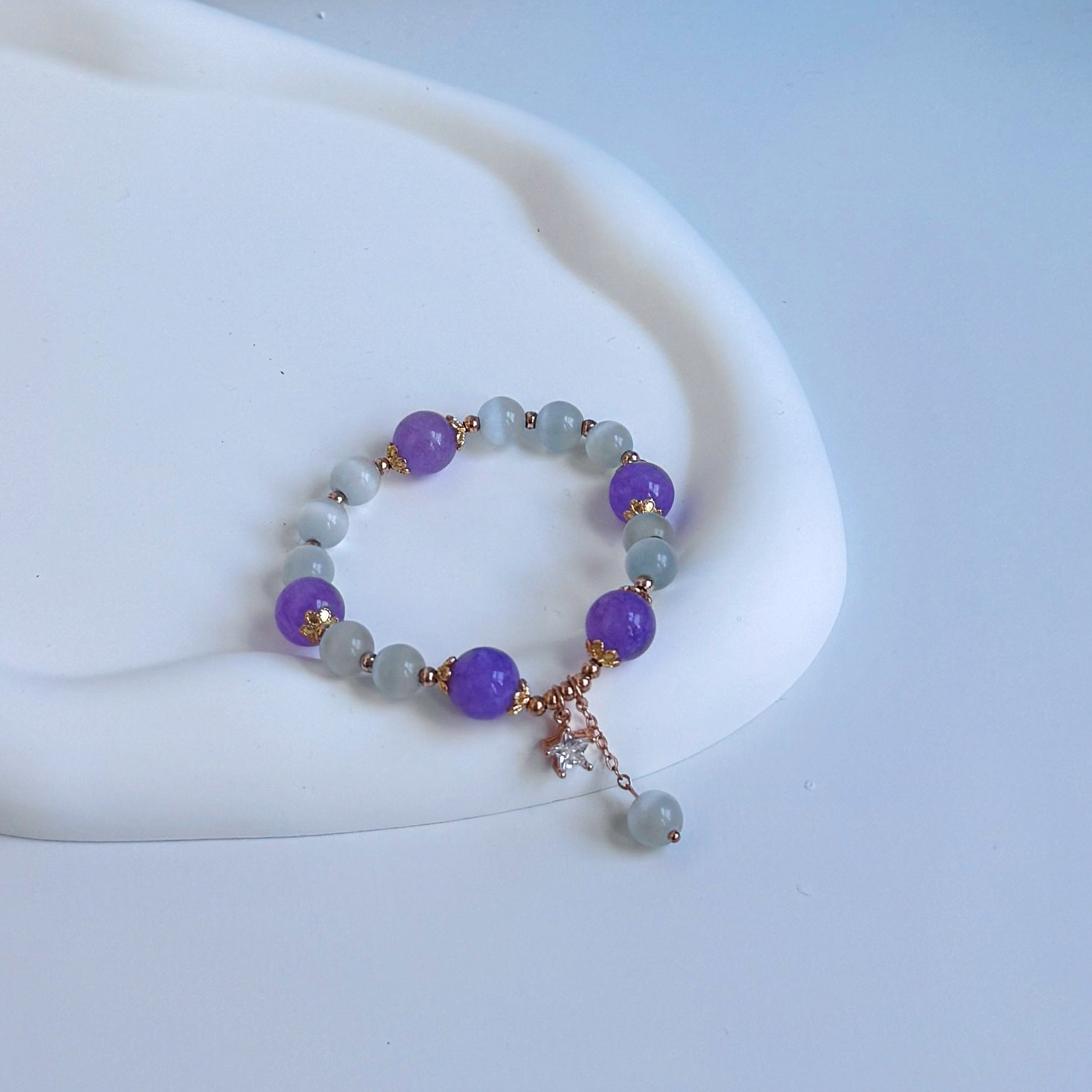 A bracelet with alternating beads of light purple amethyst and white tigers' eye.