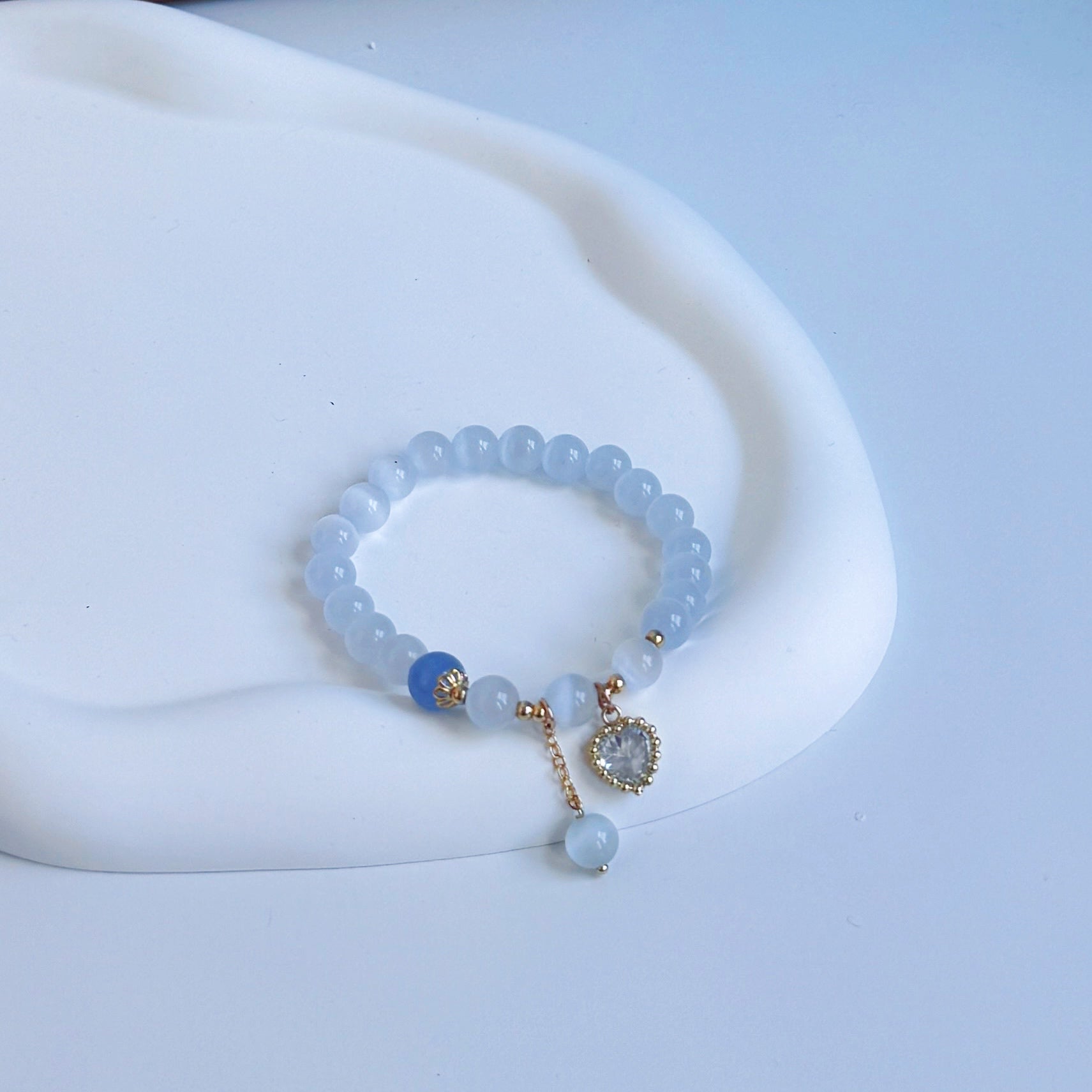 Light blue aquamarine beaded bracelet with a royal blue bead and a light blue heart charm.