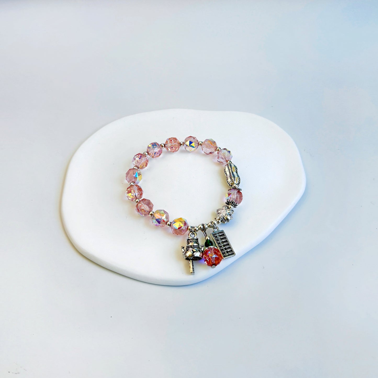 A shimmering and stunning bracelet with rose quartz beads and lucky charms, featuring light pink beads.