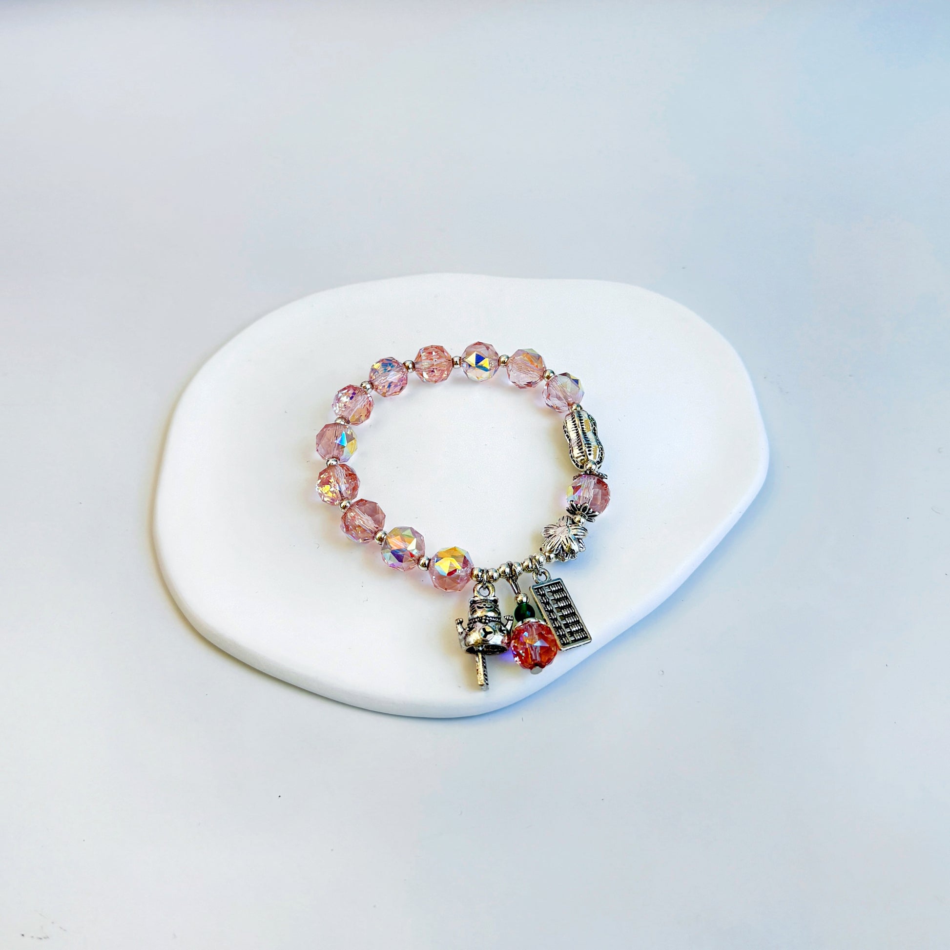 A shimmering and stunning bracelet with rose quartz beads and lucky charms, featuring light pink beads.