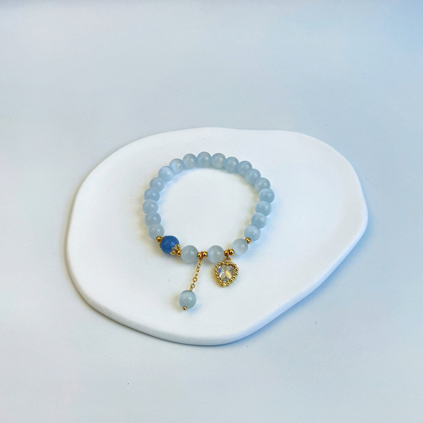 A shimmering and stunning bracelet with light blue aquamarine beads, a royal blue bead, and a heart charm, featuring light and dark blue beads.