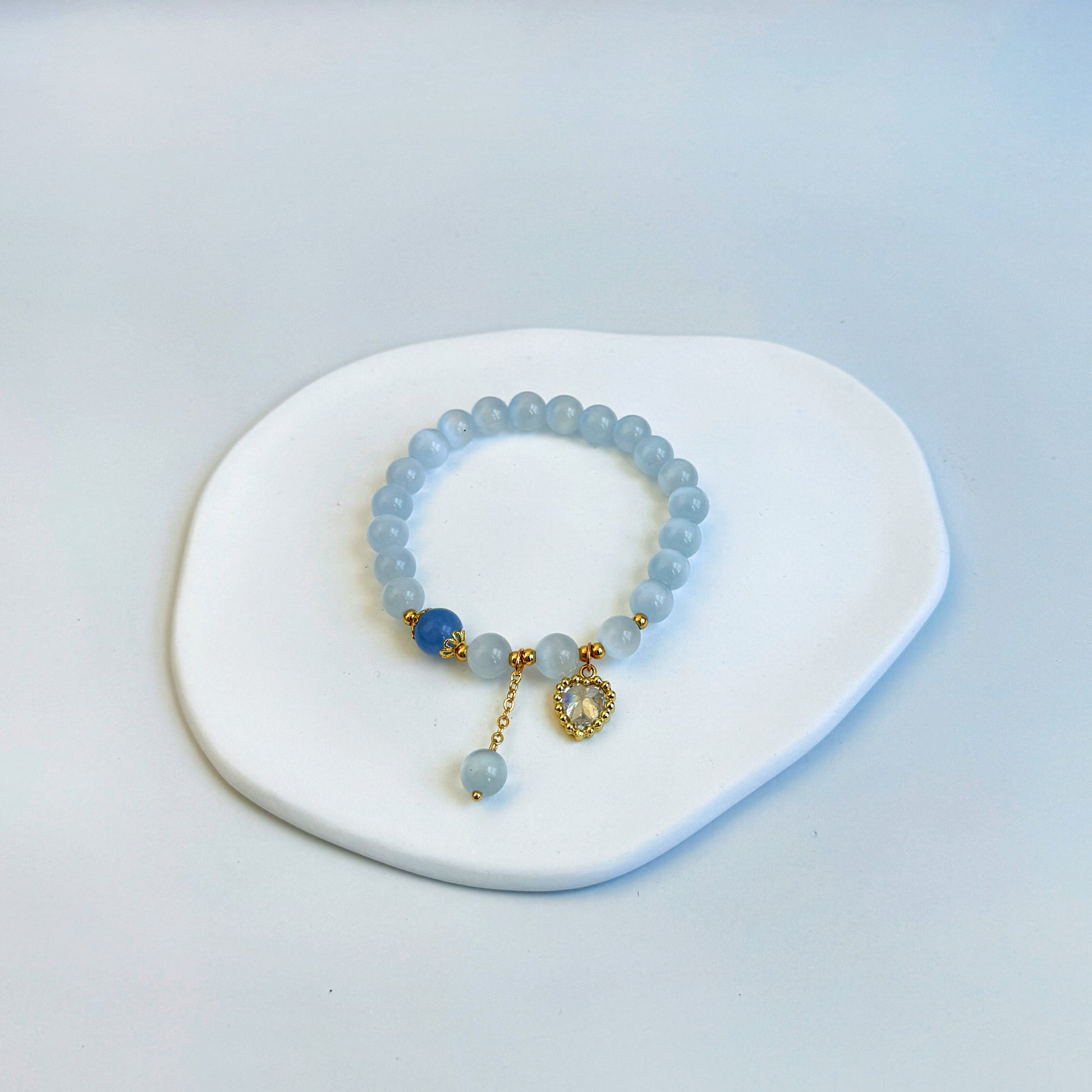 A shimmering and stunning bracelet with light blue aquamarine beads, a royal blue bead, and a heart charm, featuring light and dark blue beads.