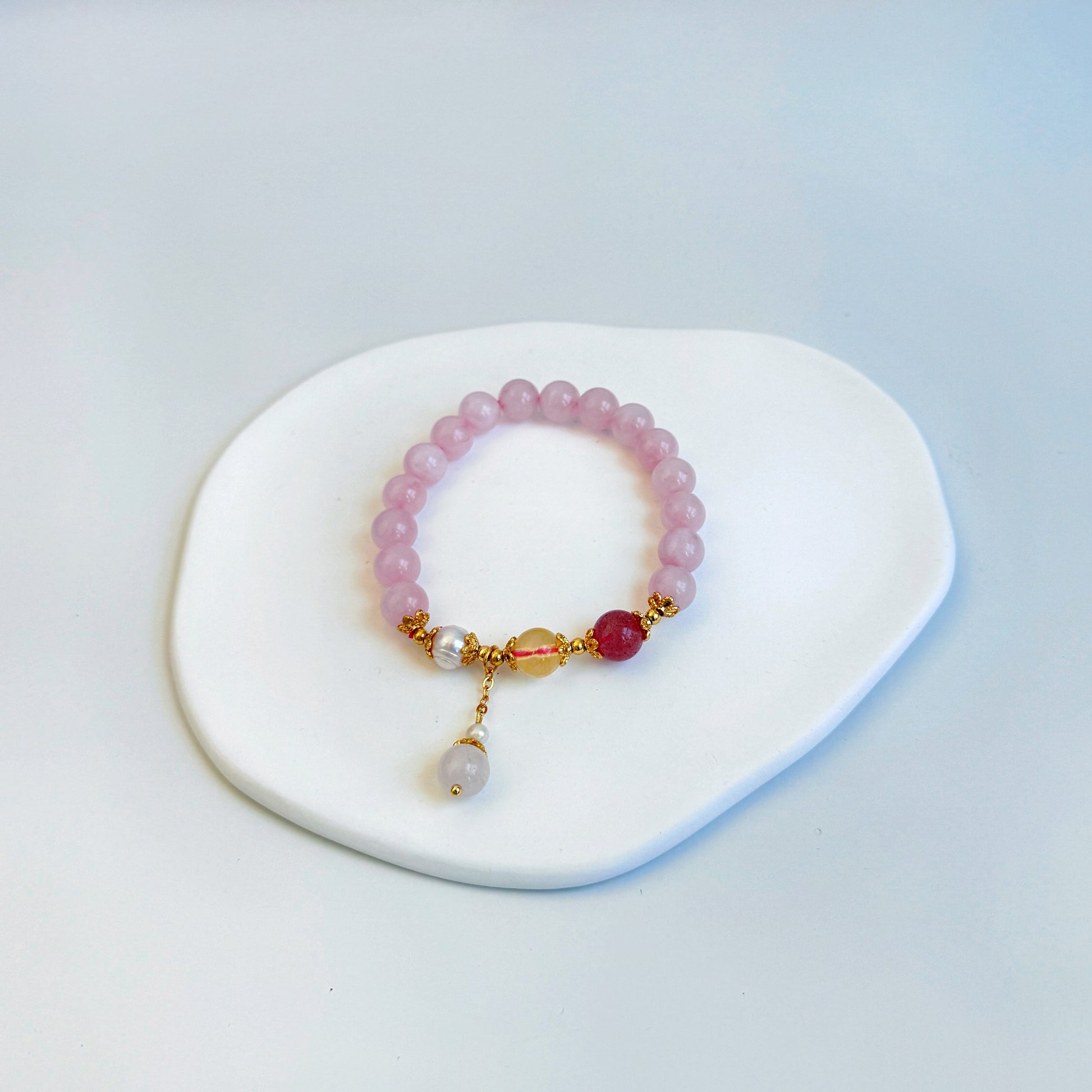 A shimmering and stunning bracelet with purple strawberry quartz, pearl, and citrine beads, featuring light purple and yellow beads.