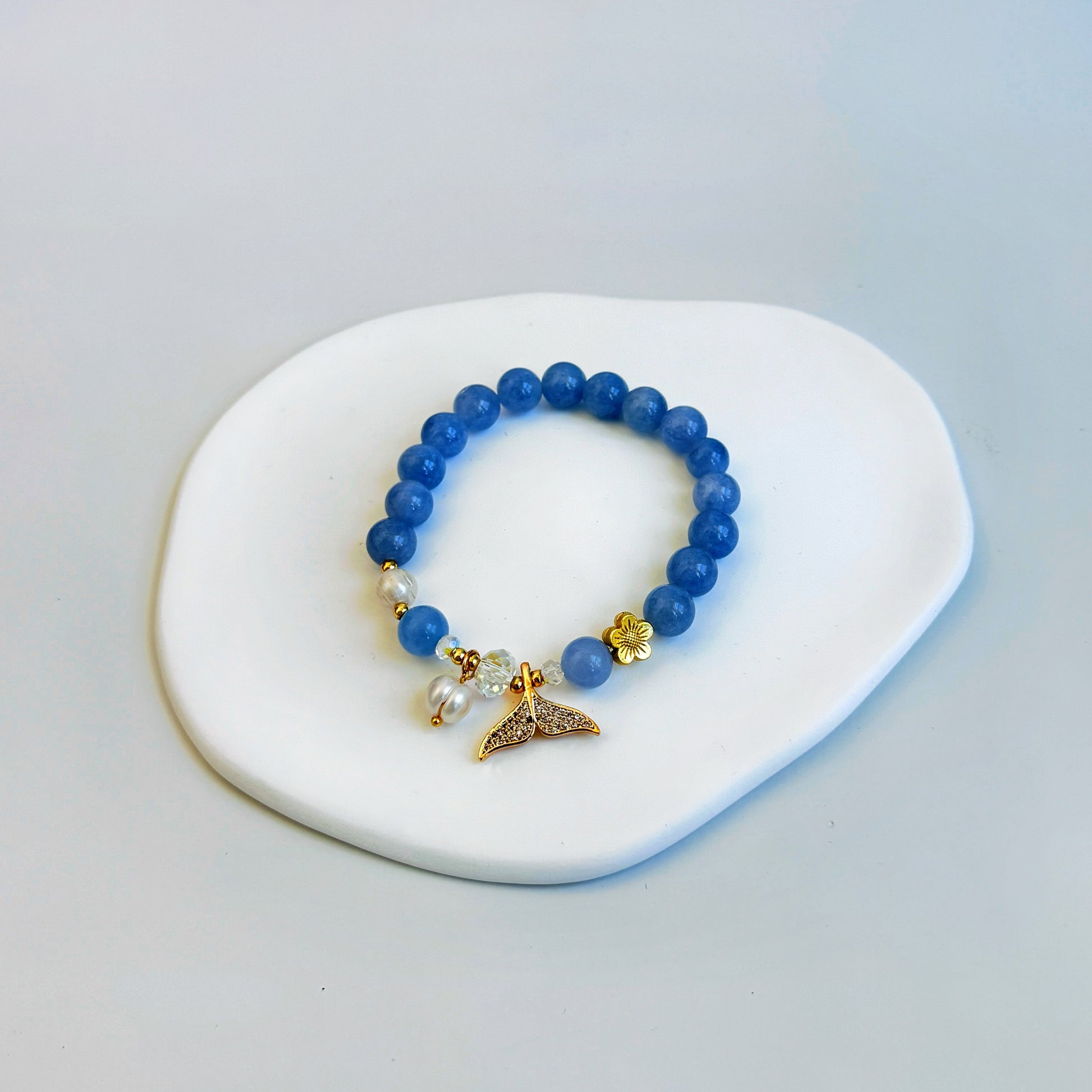 A cute bracelet with aquamarine beads, pearls, and a gold mermaid or dolphin tail charm, ideal as a gift for girlfriend, gift for sister, gift for daughter, gift for wife, or gift for friend.