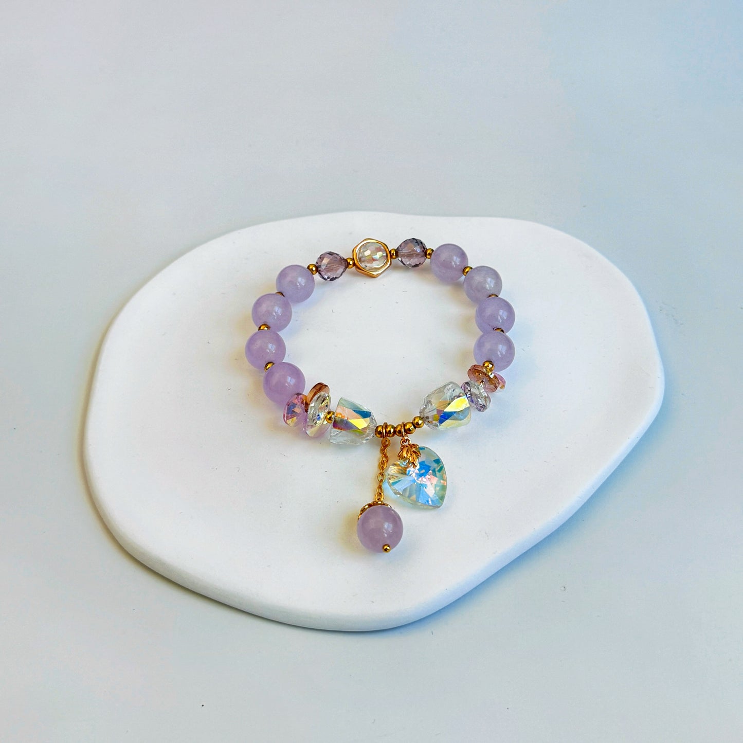 A shimmering and stunning bracelet with pink jade beads and crystal charms, featuring light pink beads.