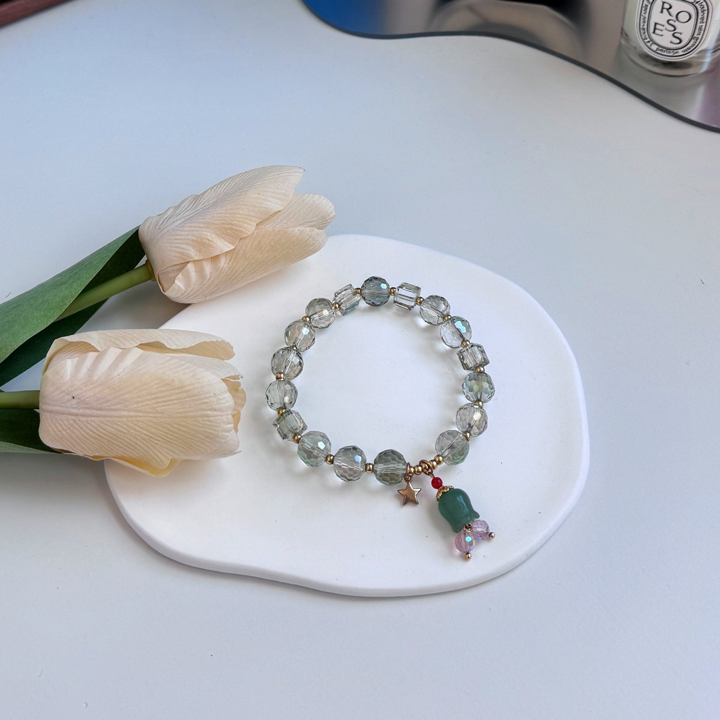 A shimmering and stunning bracelet with glass beads and a green flower charm, featuring clear beads.