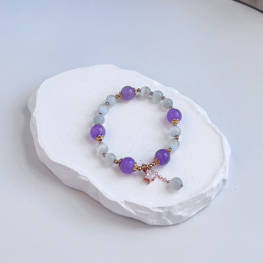 A sophisticated, pretty bracelet with 15 purple amethyst and white tiger's eye beads, each separated by a small gold colored accent bead, and with a small dangling star charm and extra tiger's eye bead.