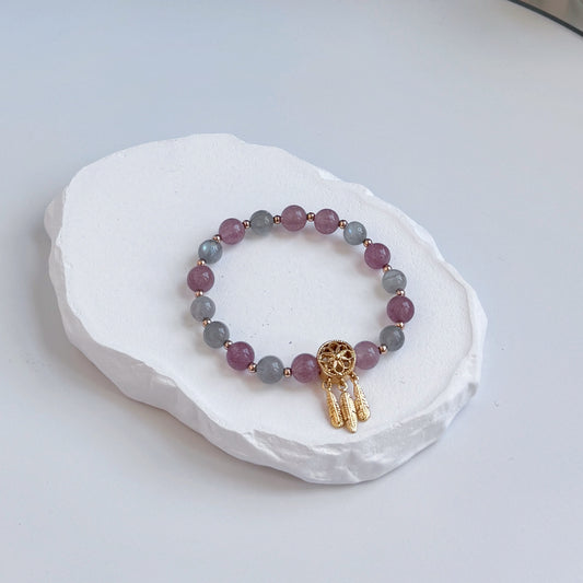 A sophisticated, pretty bracelet with 17 beads alternating between strawberry quartz and moonstone, each separated by a small gold bead, clasped with a gold dreamcatcher bead.