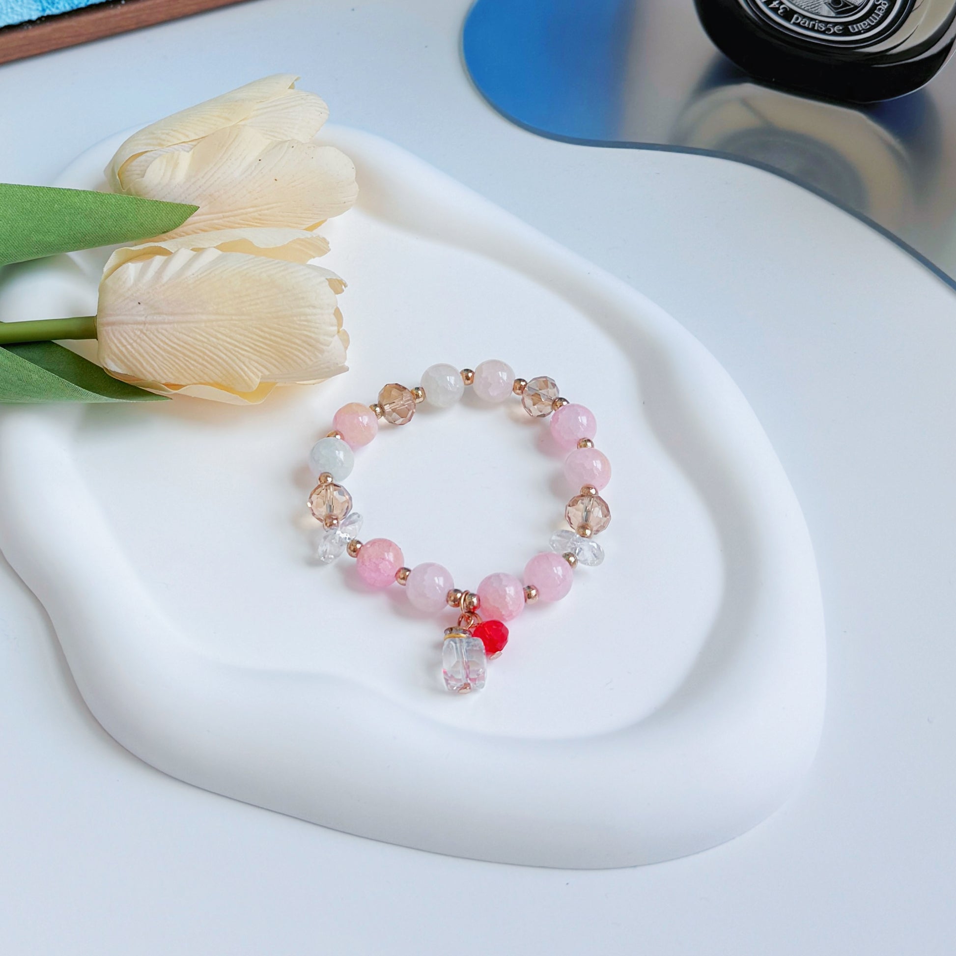 A simple and cute bracelet sitting on a mirror, ready to be worn by a fashionable young woman or given as a gift to a teen girl who likes jewelry and fashion.