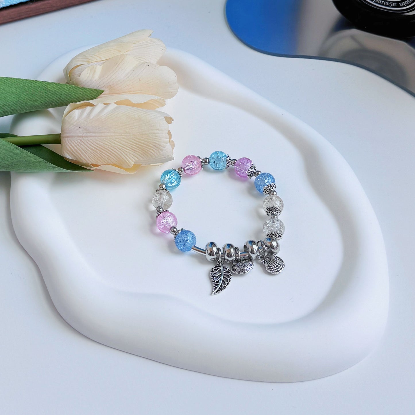 A shimmering glass bead bracelet with metal charms, perfect to add a level of fun and fashion to any outfit.