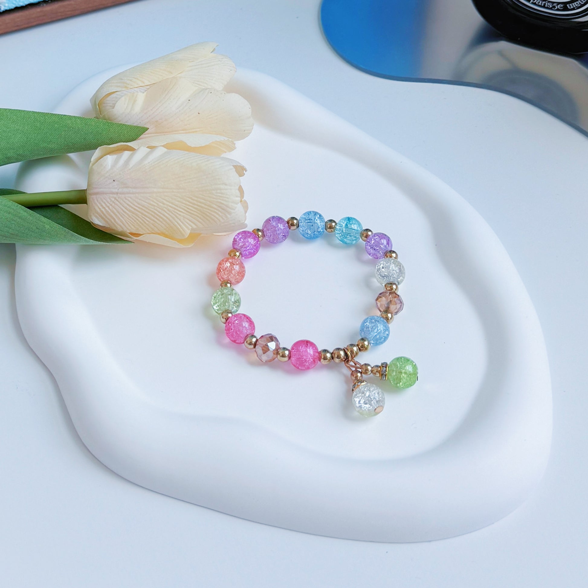 A shimmering glass beaded bracelet with bronze-colored accents, sitting on a mirror, ready to be worn by a young woman or teen girl.