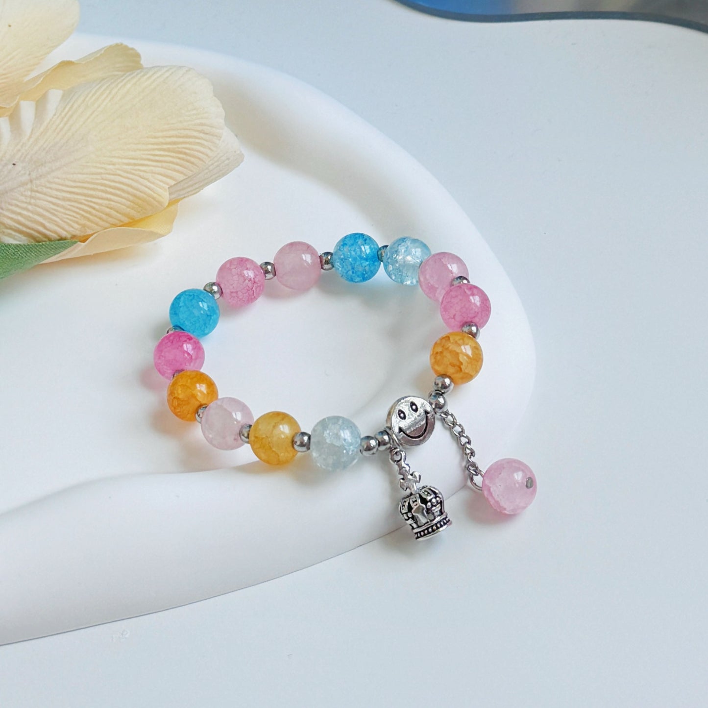 A multi-colored bracelet sitting on a glass mirror, ready to be worn by any young woman or teen girl who is fashionable and looking to add an element of elegance to her outfit.