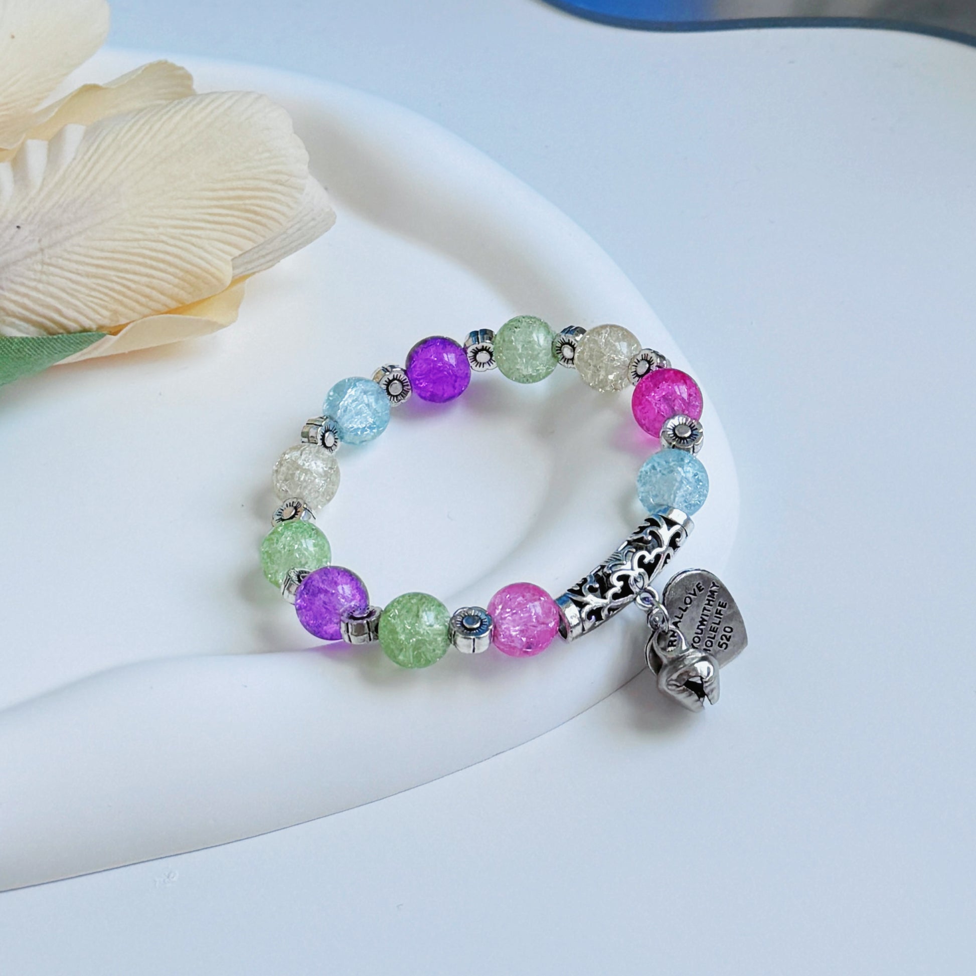 A high end bracelet with many colors of glass beads, sitting on a mirror, ready to be worn by any fashionable woman or young lady.