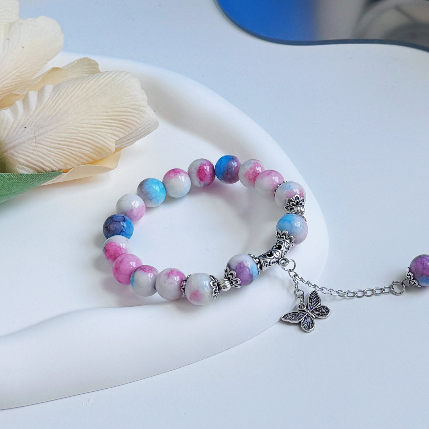 A bright and simple glass bead bracelet sitting on a glass mirror, a perfect piece of jewelry for a gift for sister, daughter, friend, girlfriend, or wife.