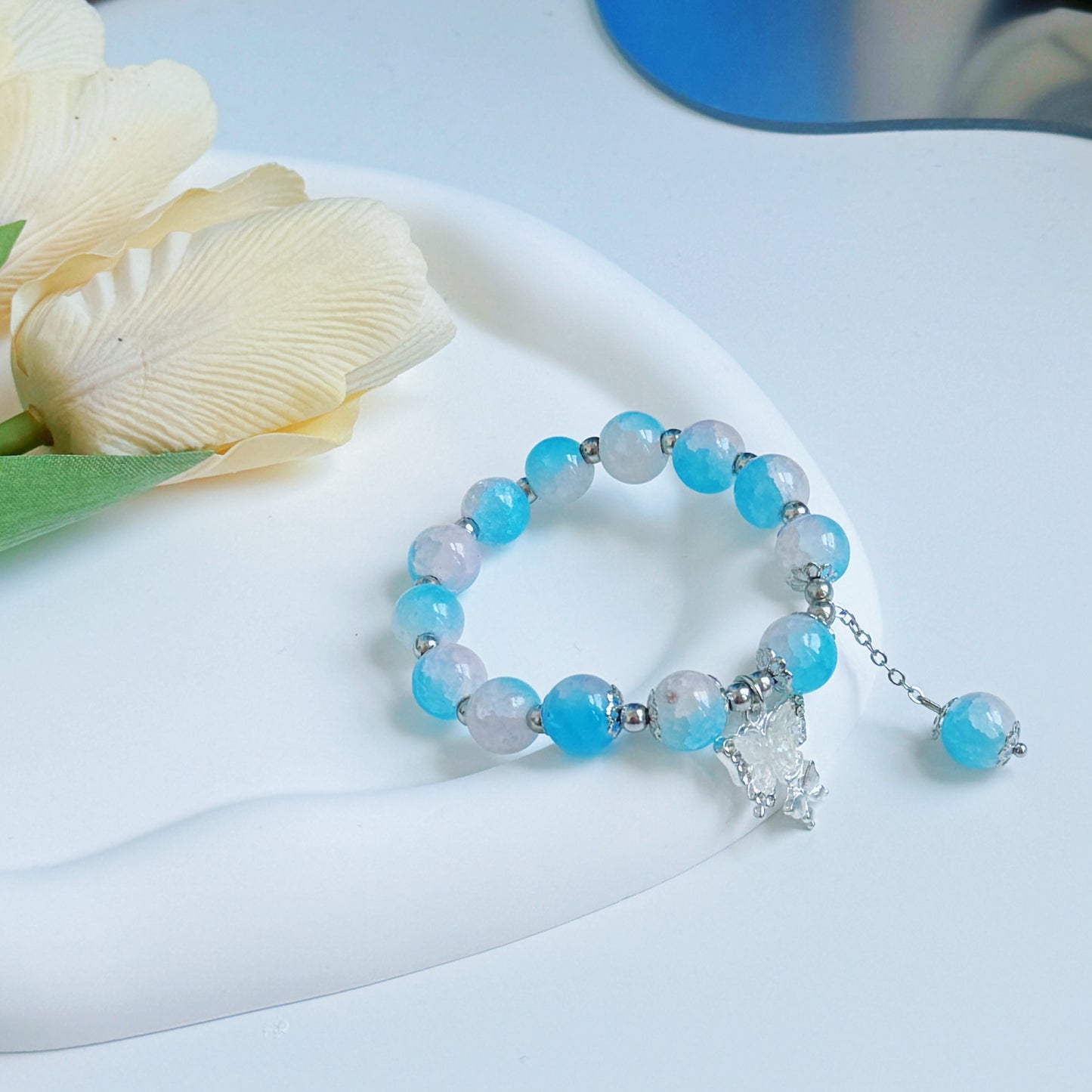 A pretty, sophisticated bracelet with a butterfly charm sitting on a glass mirror, perfect for a gift for girlfriend, gift for female friend, gift for sister, gift for wife, or gift for mom.