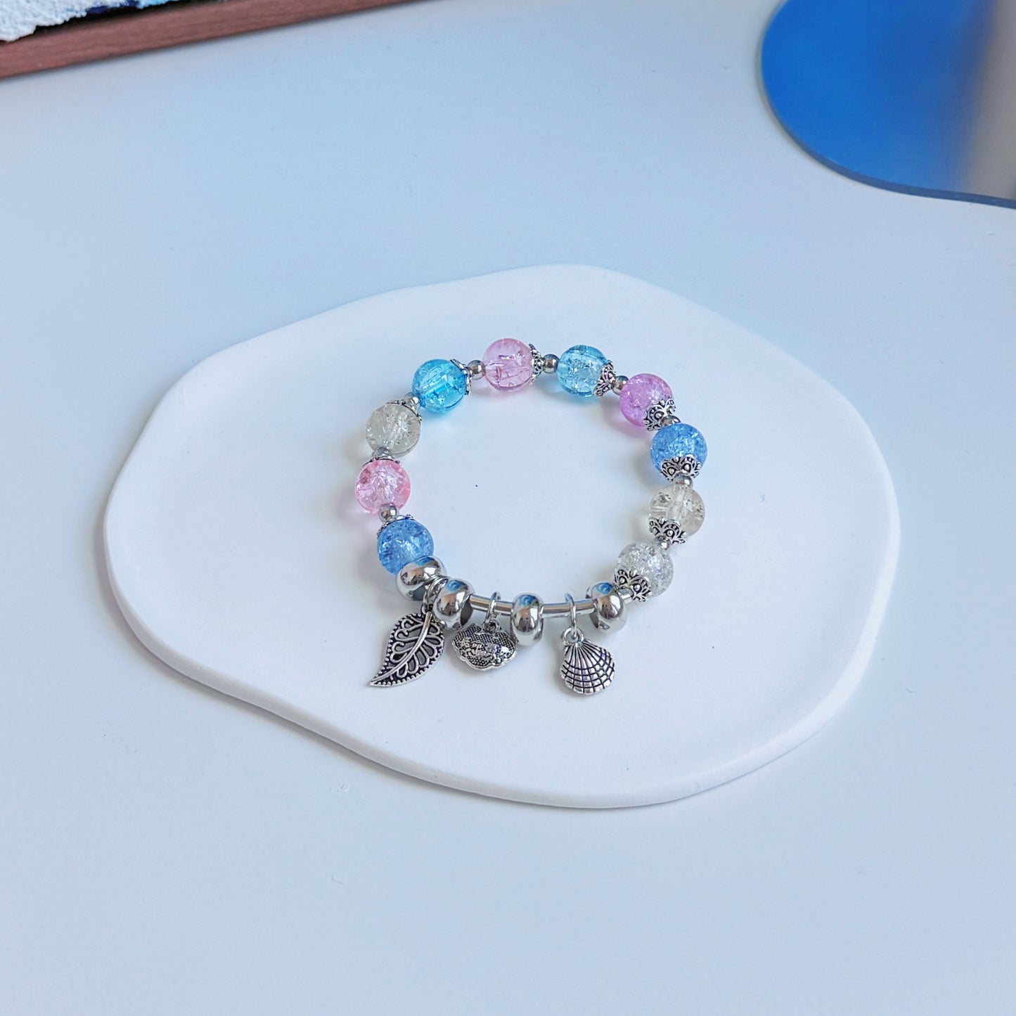 A simple, cute bracelet with multicolored sparkling glass beads and metal charms resembling the colors and shapes of an underwater paradise.