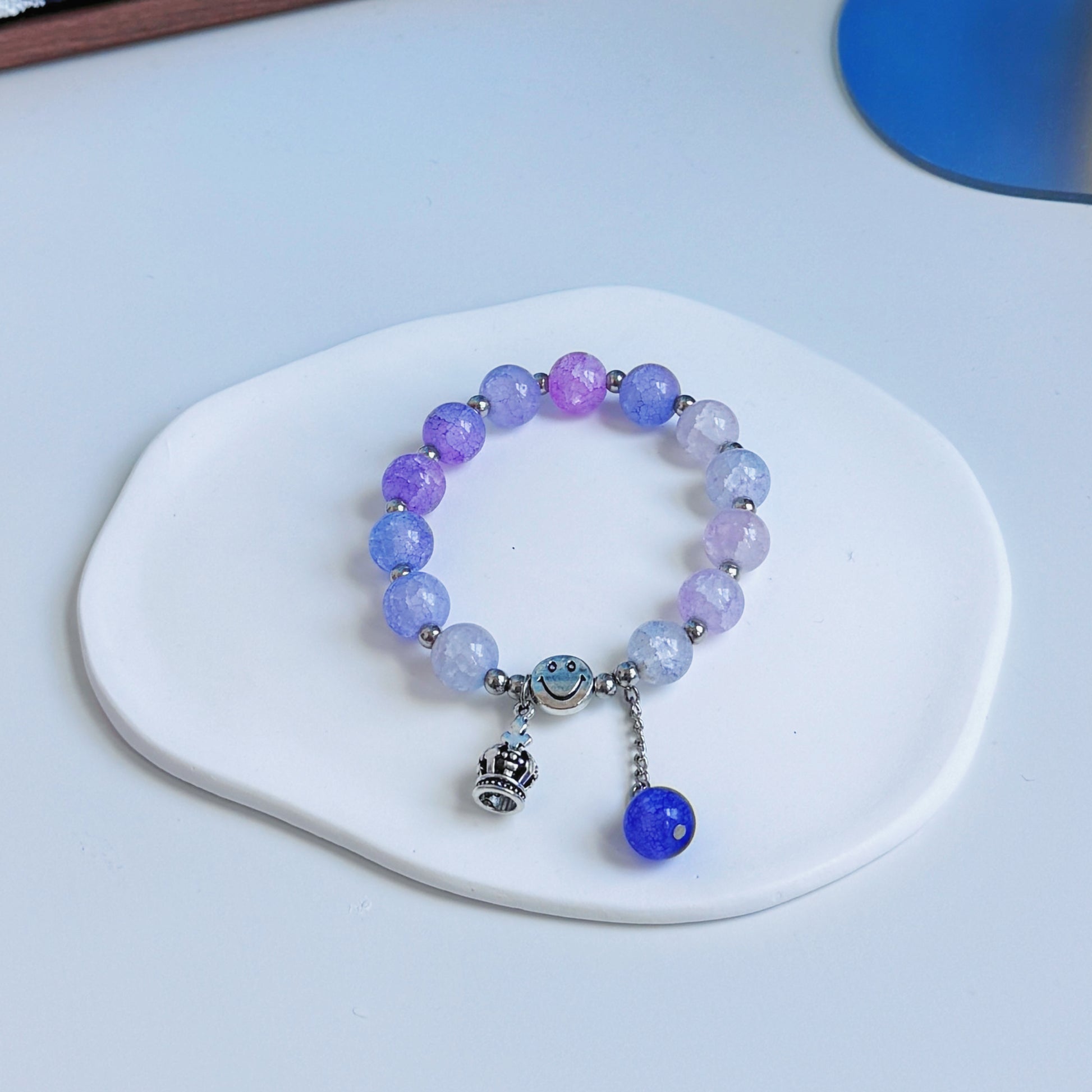 A simple, light purple glass beaded bracelet with a crown charm.