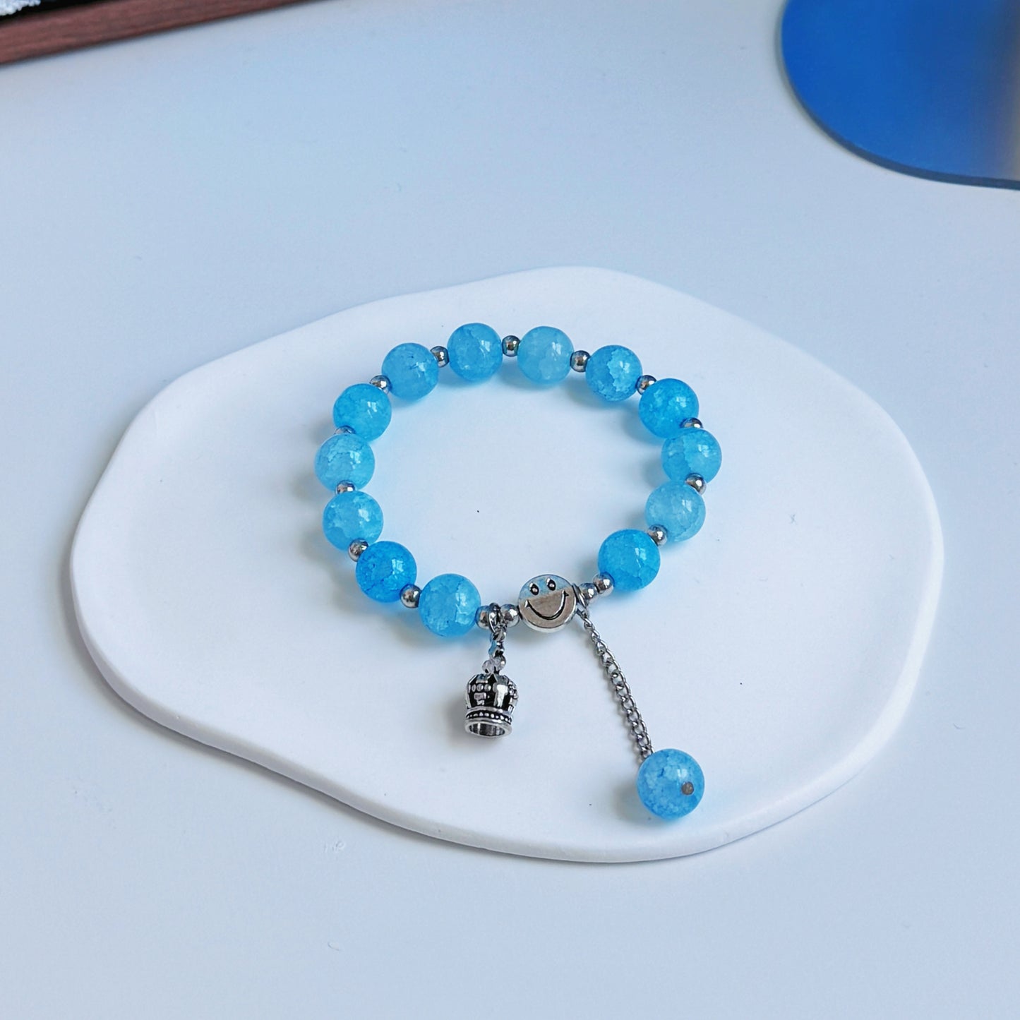 A simple, pretty bracelet with light blue glass beads and a crown charm, a perfect fashion accessory for any fashionable outfit.