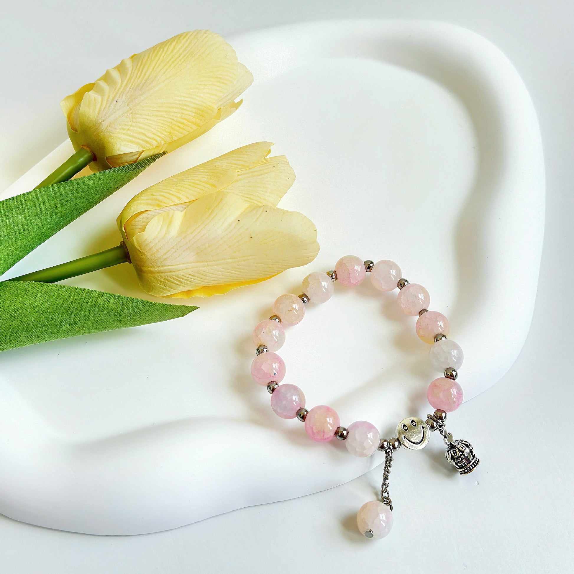 A pink bracelet with glass beads and a crown metal charm, ready to be worn by any fashionable young woman or teen girl.