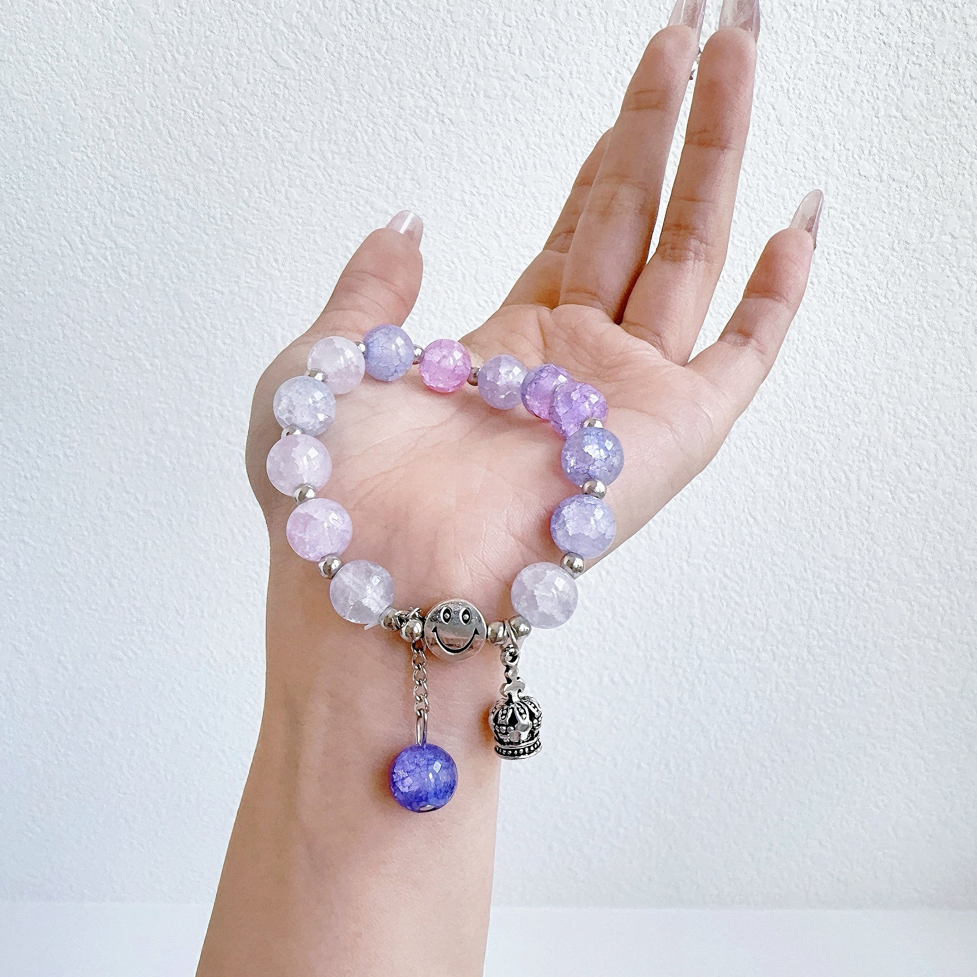 A simple, light purple bracelet with a crown charm, ready to be worn on the wrist of a fashionable young woman, or teen girl.