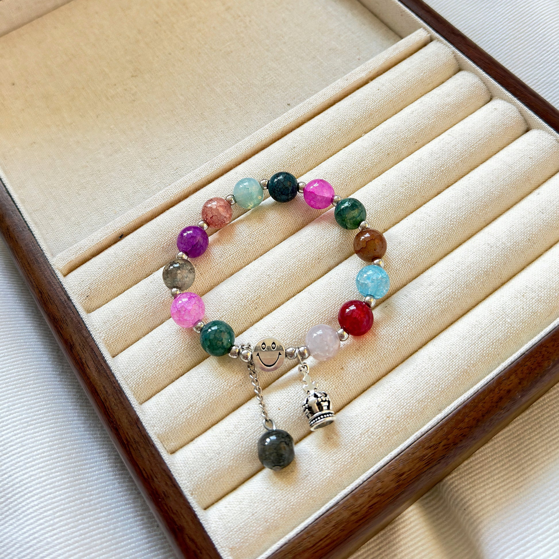 A multi-colored simple glass bracelet sitting in a warm jewelry box.