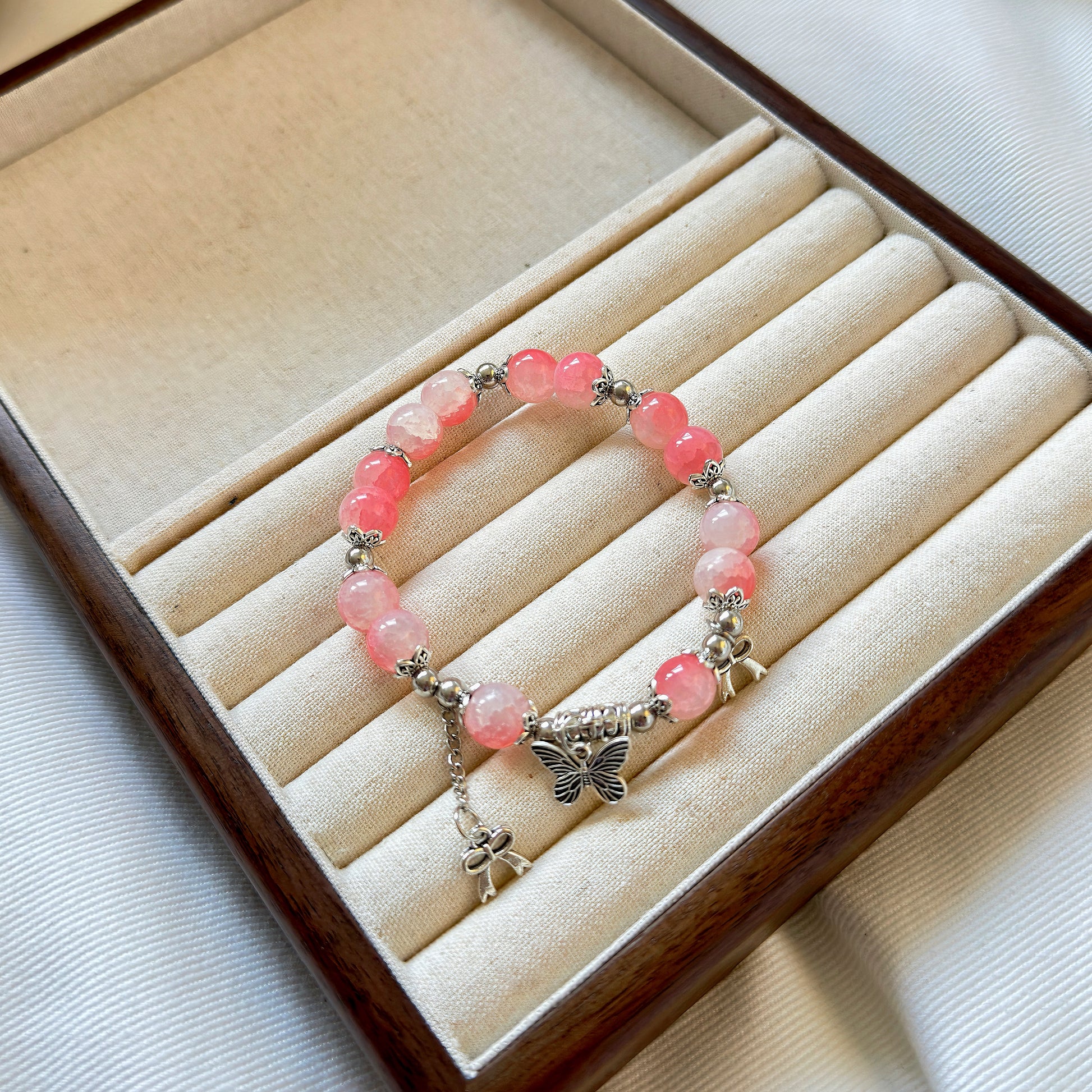 A pretty pink, glass bead bracelet sitting in a warm jewelry box, ready to enchant the wrist of any fashionable young woman or teen girl.