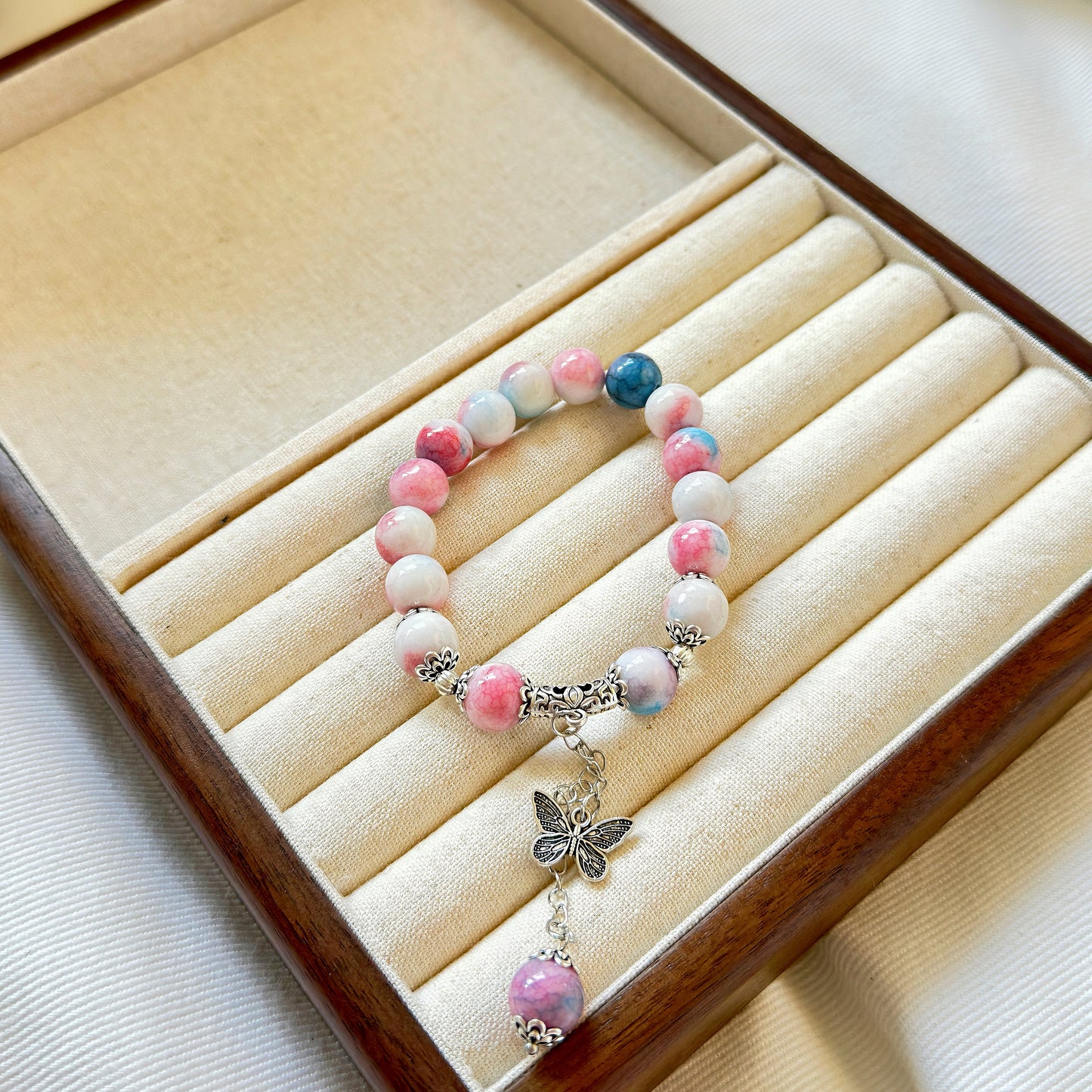 A glass bead bracelet with stunning pearly colors, sitting in a warm wooden jewelry box.